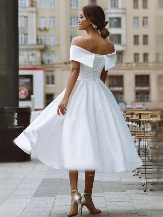White satin off-shoulder A-line wedding dress with draped bodice and flared skirt