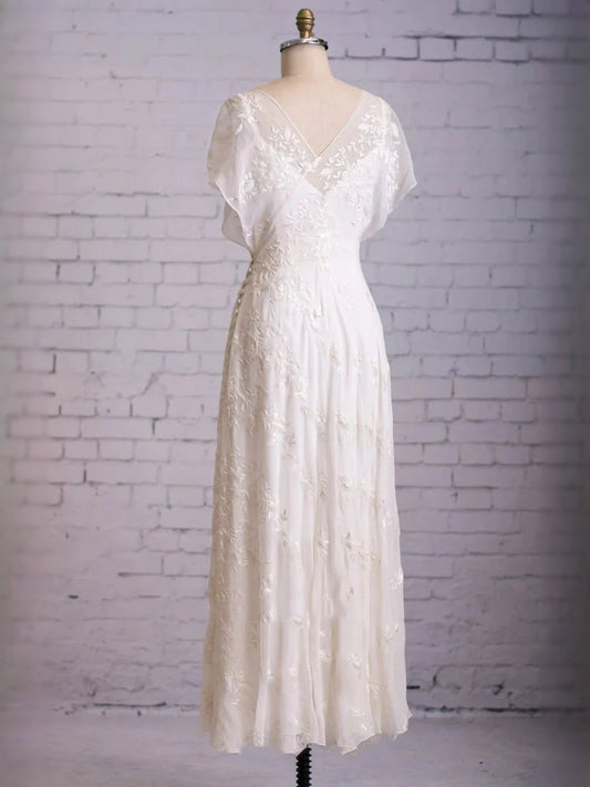 White V-neck wedding dress on mannequin, short flutter sleeves, fitted A-line skirt