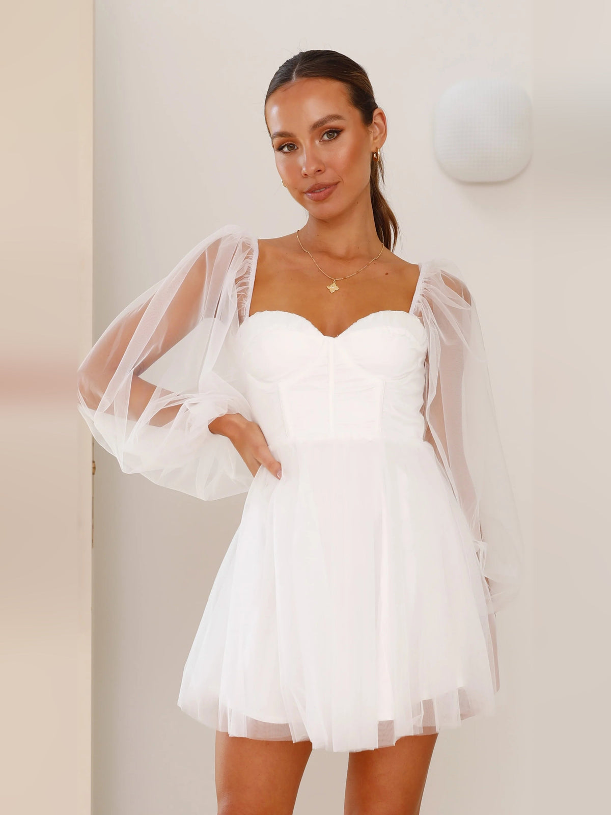 White mini dress with sweetheart neckline and sheer long puff sleeves, fitted bodice
