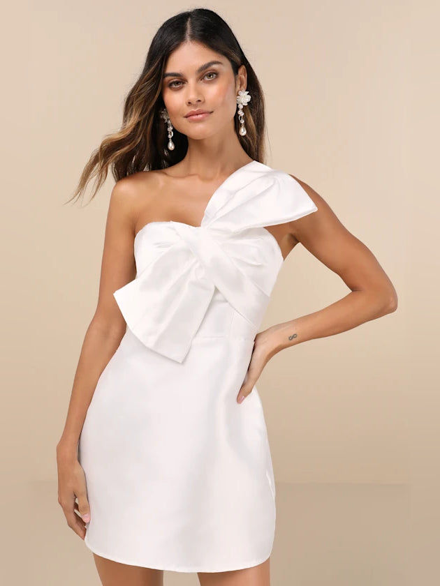 White one-shoulder mini dress with large bow detail and layered ruffle overlay