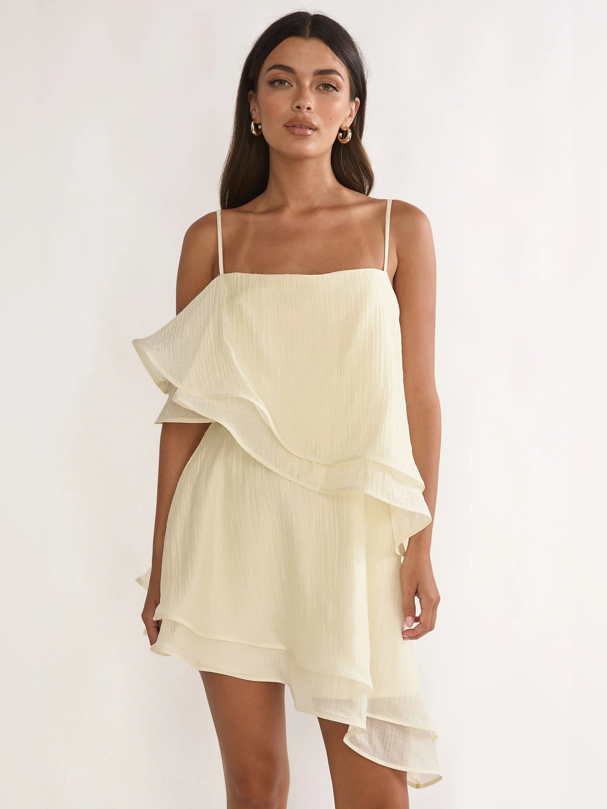 Cream layered asymmetrical mini dress with spaghetti straps and ruffled tiers