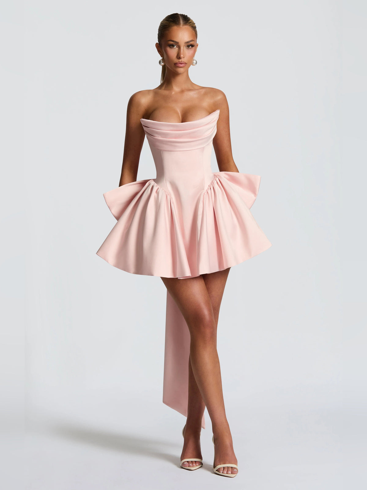 Blush strapless mini dress with draped bodice and full ruffled skirt with side bows