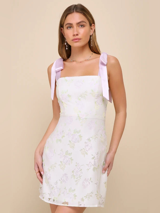 Cream floral mini homecoming dress with lilac bow shoulder straps and square neckline