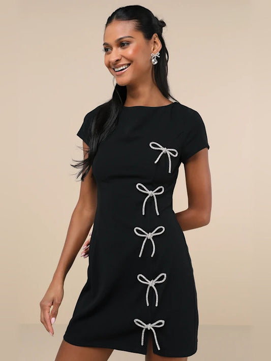 Black short-sleeve mini dress with rhinestone bow accents and bow-tie details at waist
