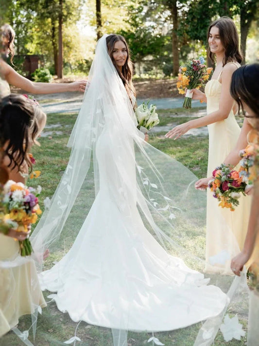 White strapless mermaid wedding dress with flowing train and veil, front on bride