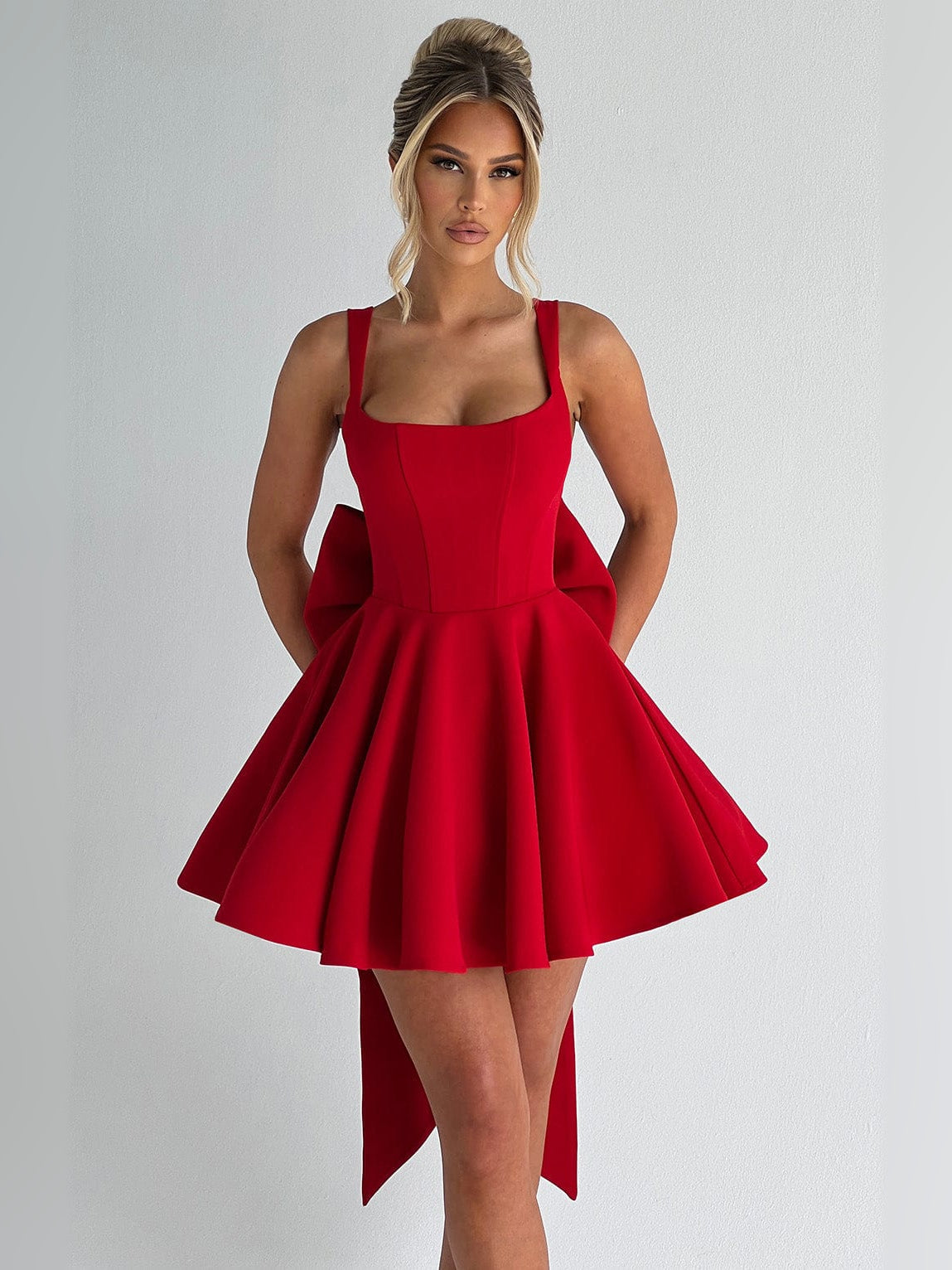 Red sleeveless mini dress with square neckline and flared skirt with draped side panels