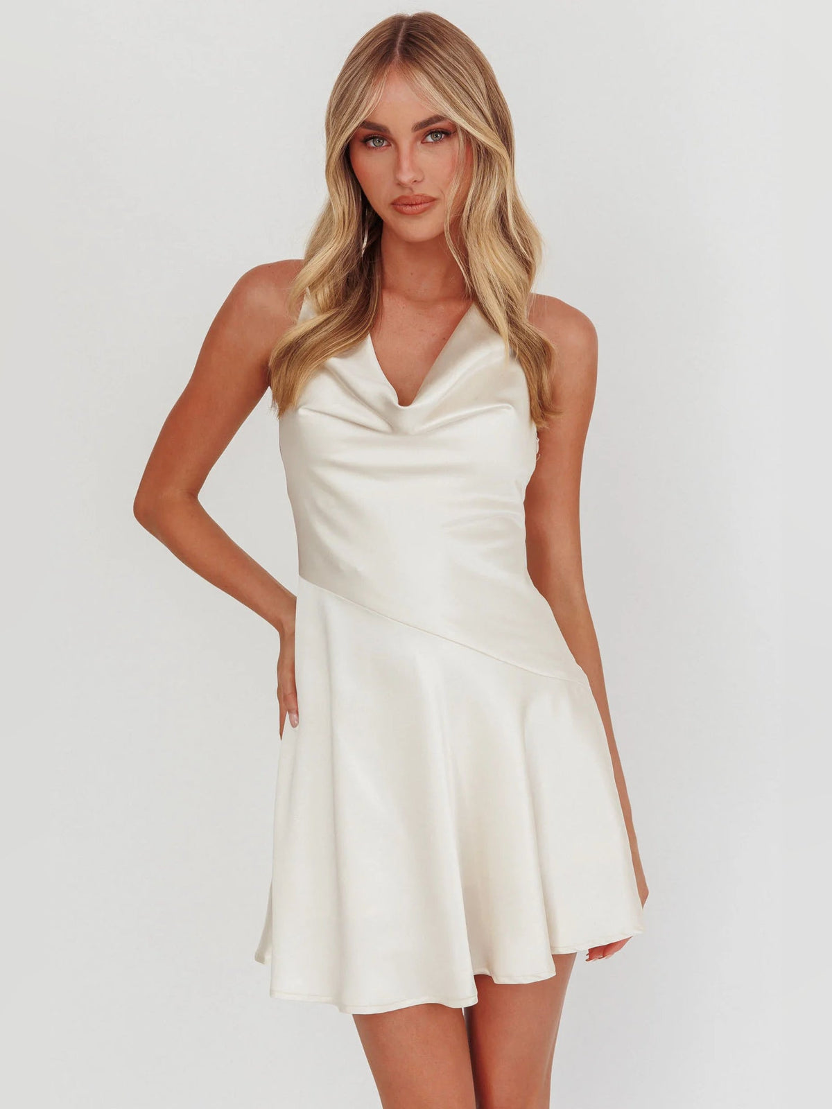Ivory cowl-neck mini homecoming dress with sleeveless bodice and draped waist.