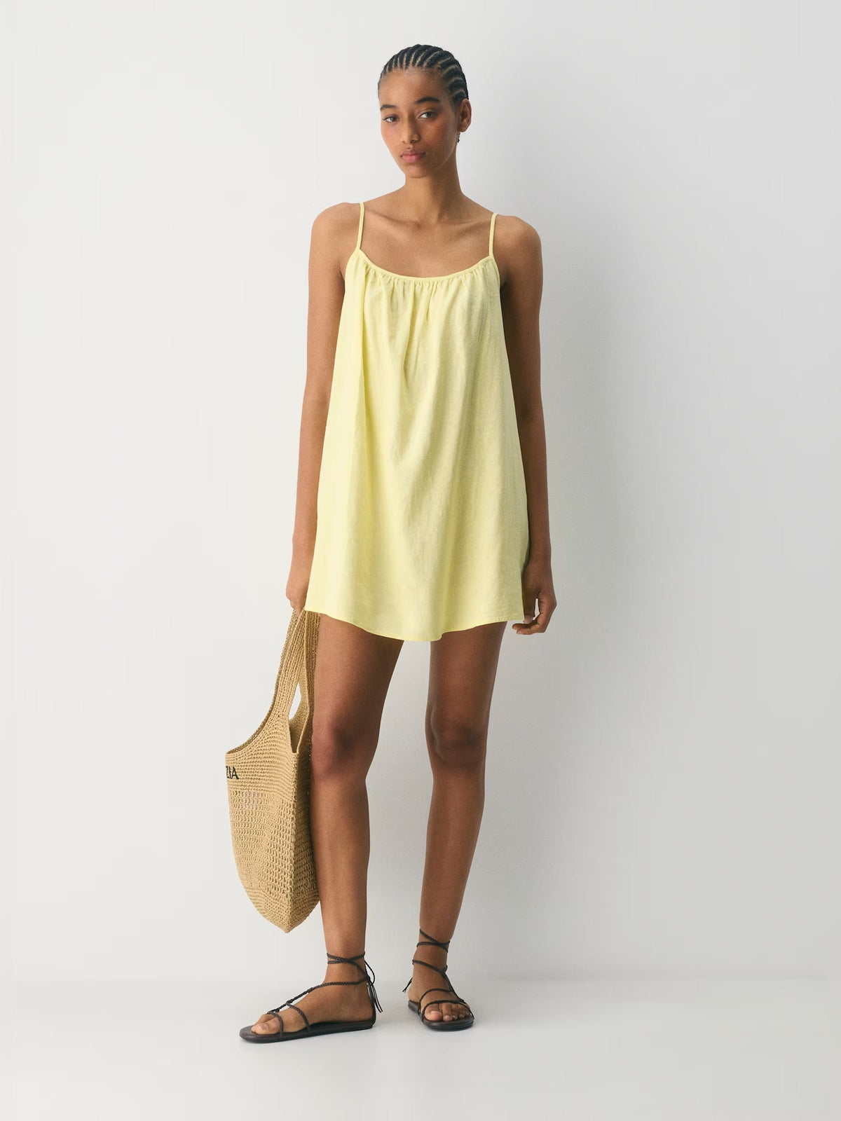 Light yellow mini homecoming dress with thin straps, scoop neckline, and gathered bust