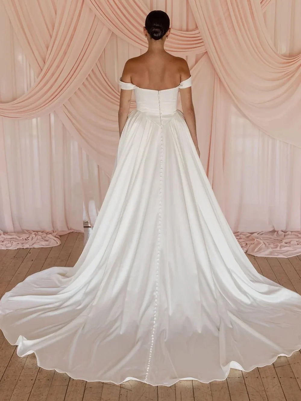 Ivory off-shoulder satin ball-gown wedding dress with draped bodice and full skirt