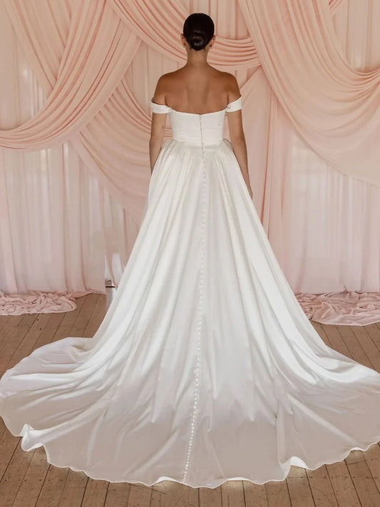 Ivory off-shoulder satin ball-gown wedding dress with draped bodice and full skirt
