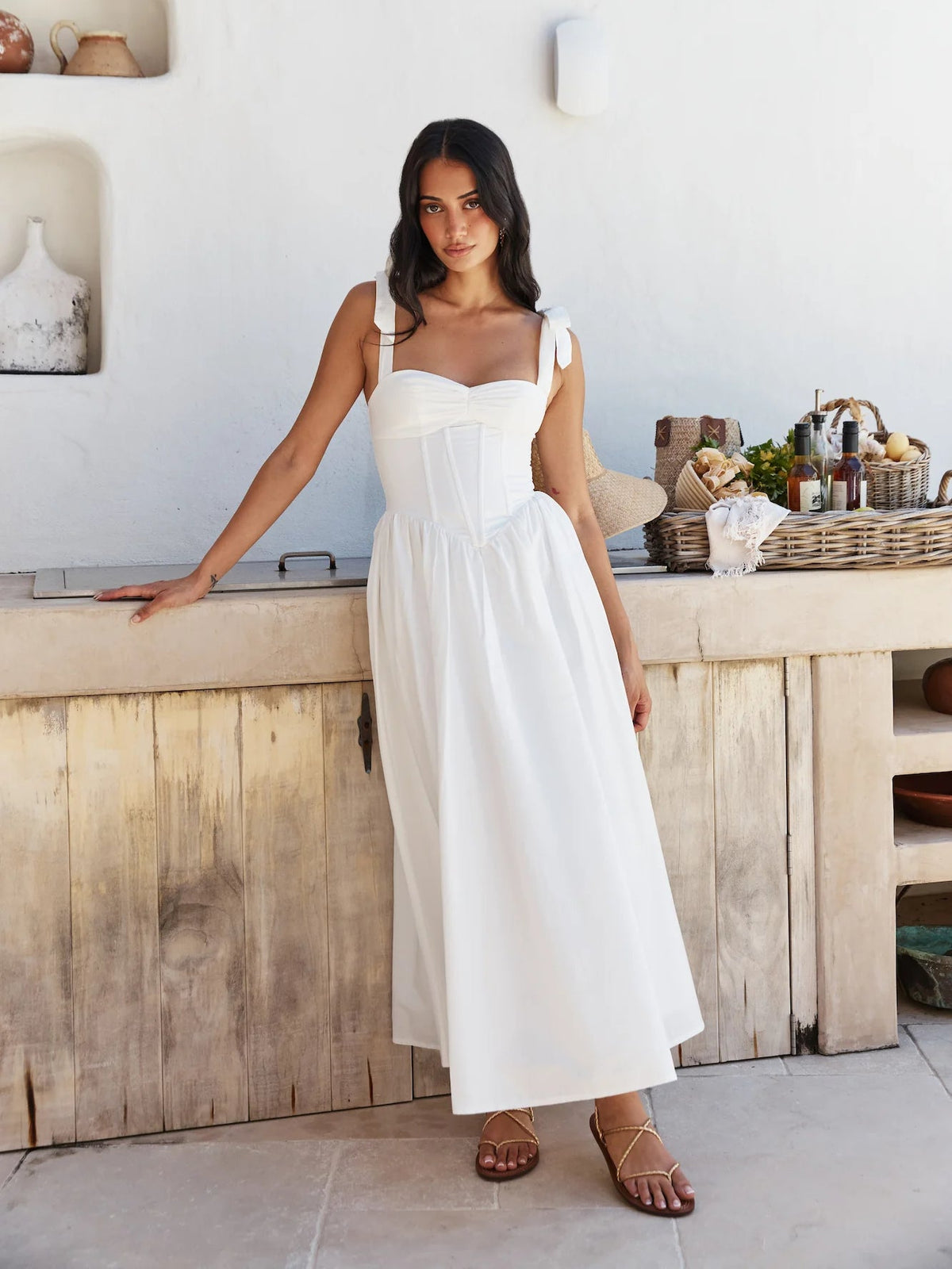 White midi formal dress with square neckline, bow spaghetti straps, and gathered skirt.