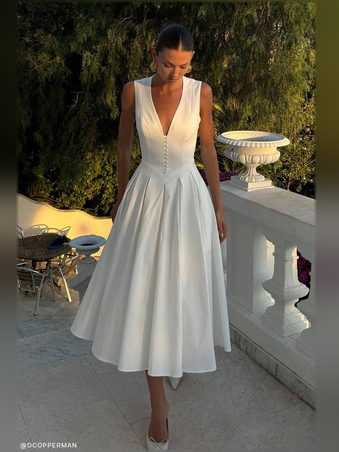 White sleeveless midi formal dress with deep V-neck and pleated skirt detail