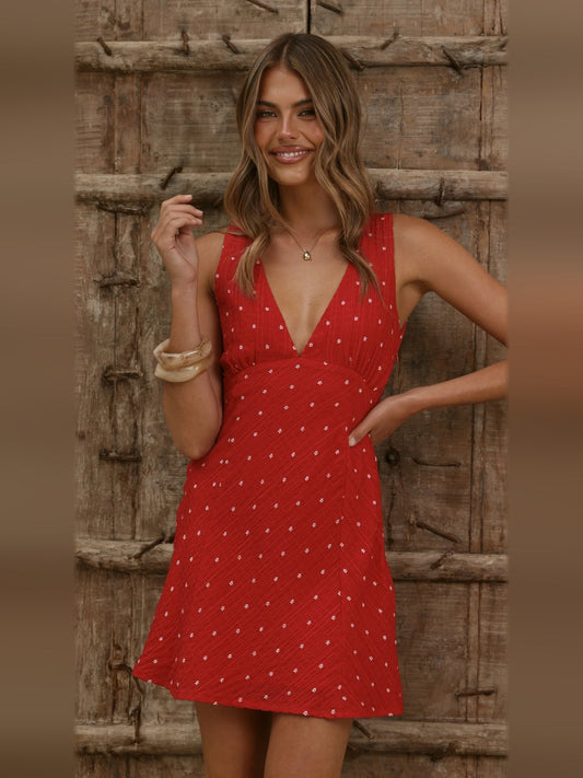 Red mini homecoming dress with V-neck, sleeveless design, and small white dot pattern