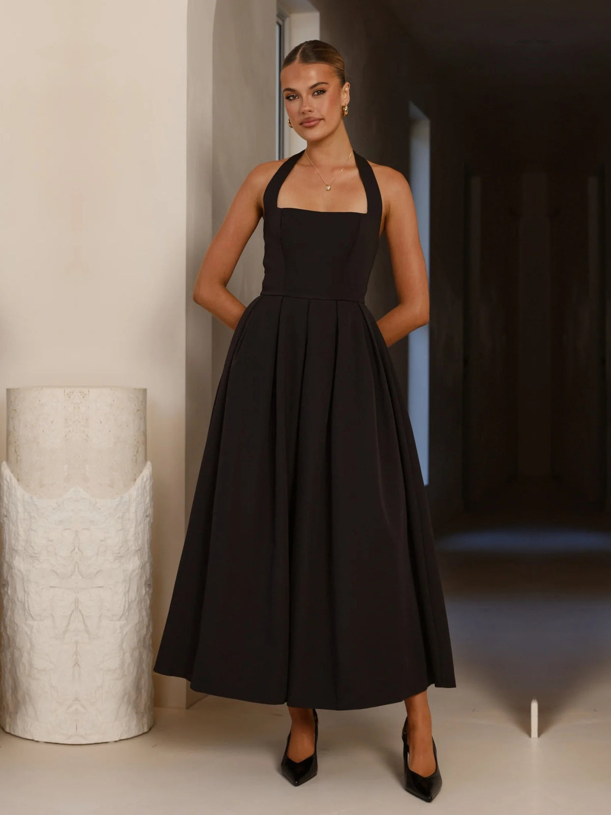 Black a-line maxi formal dress with halter neckline, full-length front view