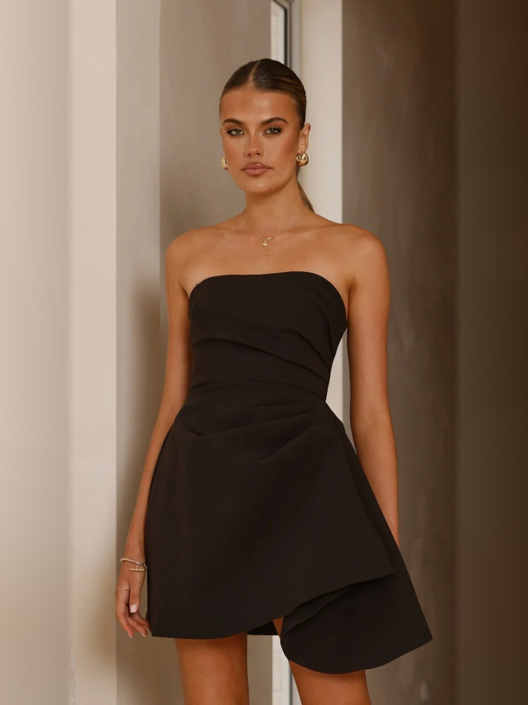Black strapless mini dress with draped bodice and layered asymmetrical hem