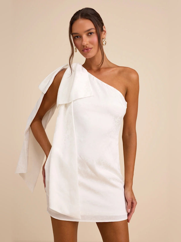 White one-shoulder mini satin dress with draped sash and bow detail