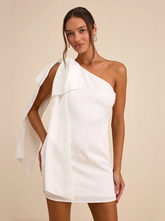 White one-shoulder mini satin dress with draped sash and bow detail