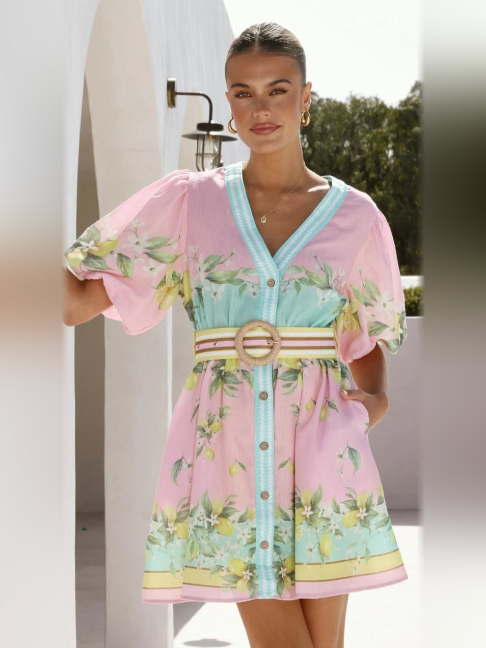 Pink mini homecoming dress with V-neck, turquoise trim, puff sleeves, floral print, belt.