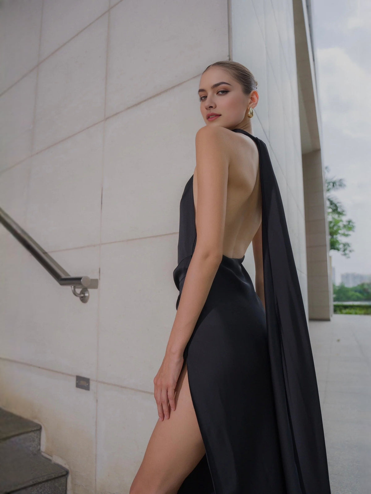 Black satin halter sheath gown with draped back and thigh-high slit