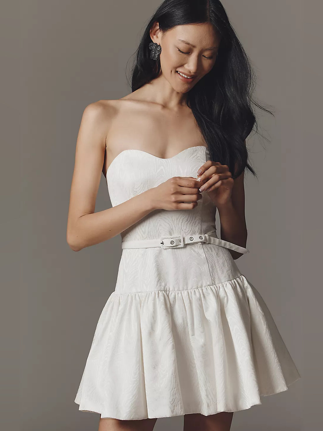 White strapless mini dress with sweetheart bodice, belt with grommets, tiered skirt