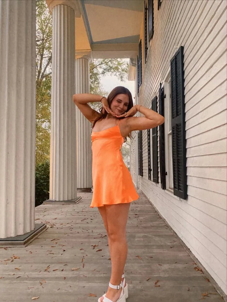 Orange satin mini slip dress with square neckline and spaghetti straps, open back.