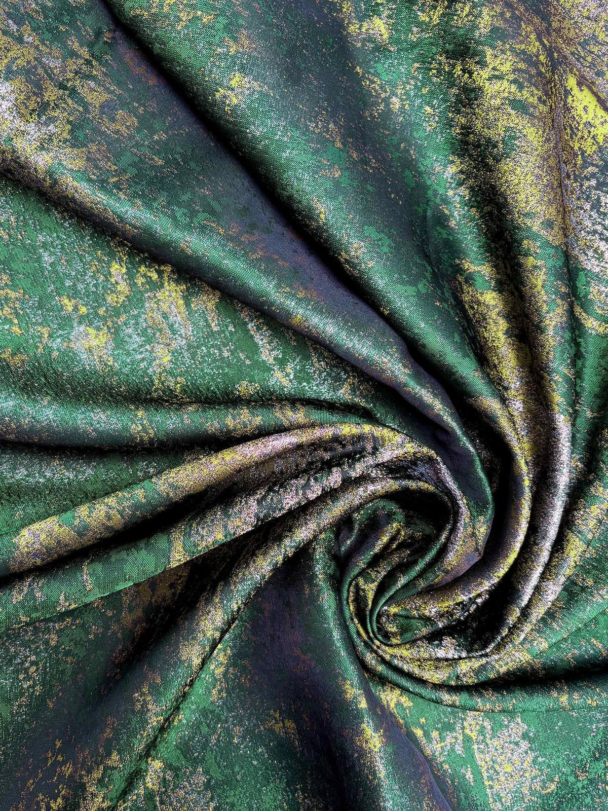 Close-up of green and gold metallic floral fabric with draped folds