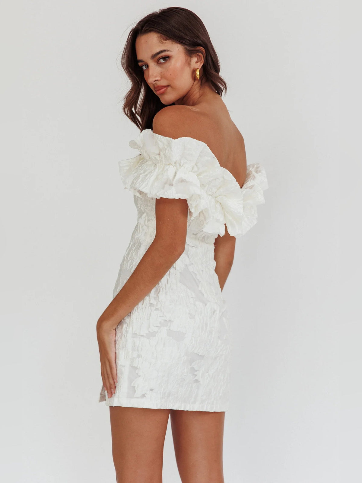 White off-shoulder mini dress with ruffle sleeves, textured bodice, and angled side slit