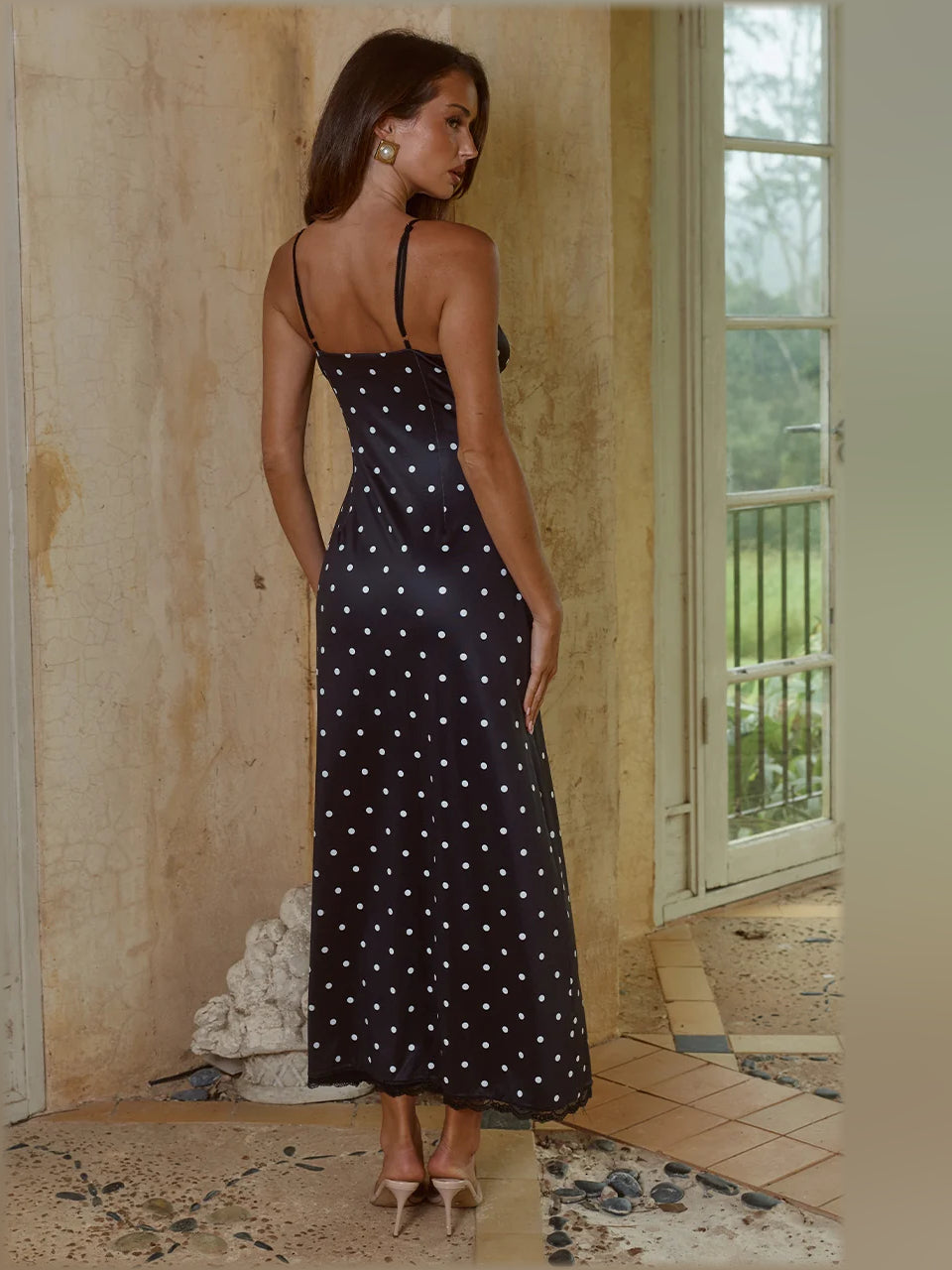 Black polka-dot camisole midi dress with lace-trim neckline and spaghetti straps, side view