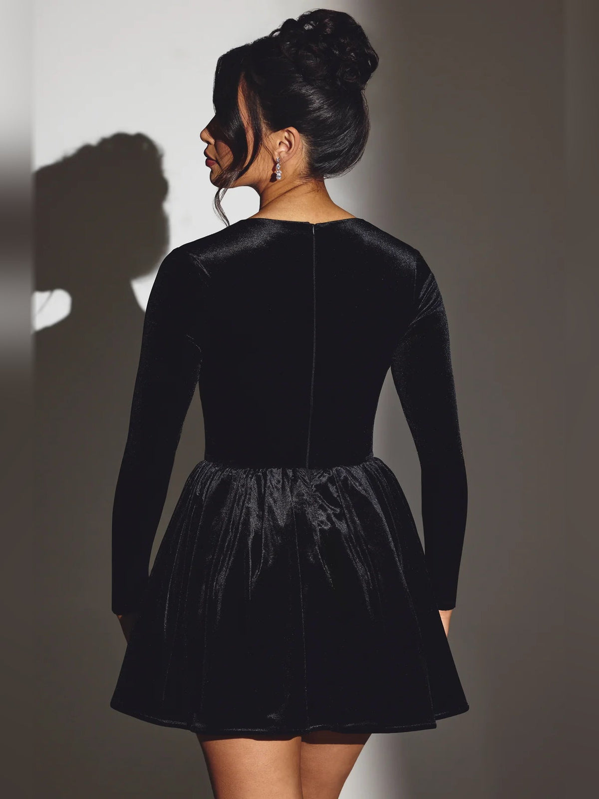 Black velvet long-sleeve corset mini dress, viewed from the back with flared skirt