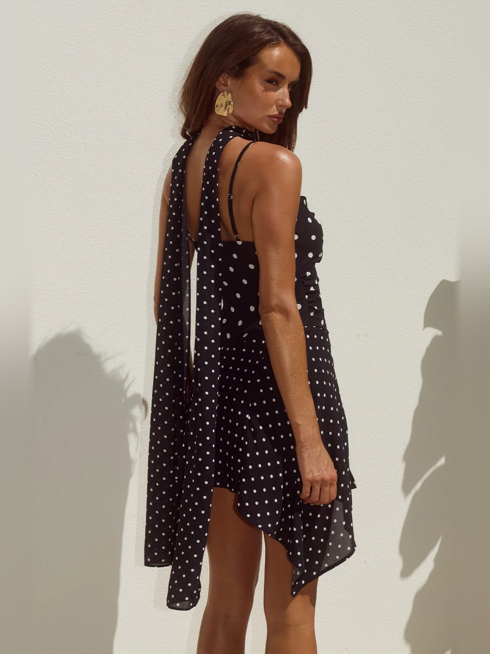 Black polka-dot mini dress with scoop neckline, thin straps, open back, asymmetrical hem