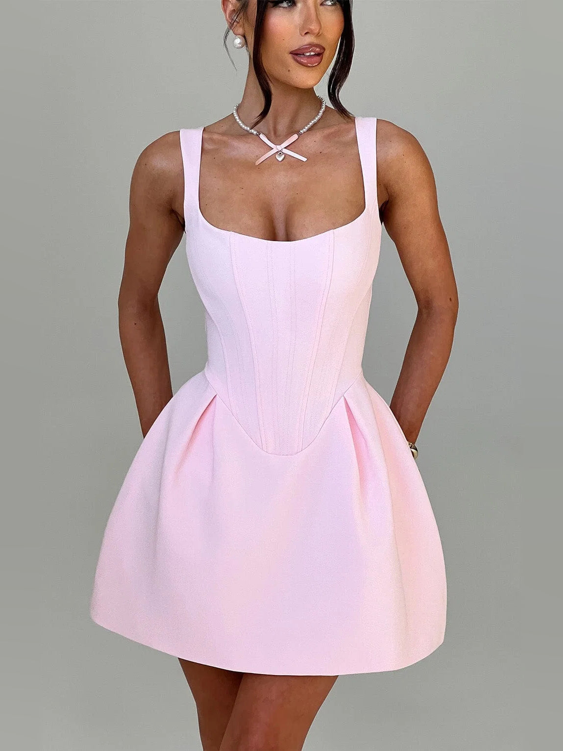 Sleeveless blush mini dress with spaghetti straps, corset seams, and flared skirt