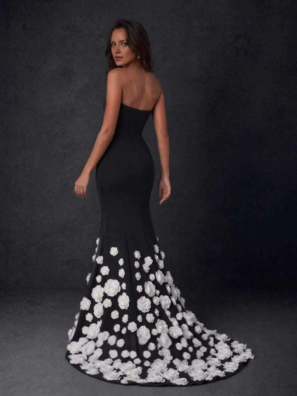 Black strapless formal gown, back view, covered in white rose appliques along flared hem