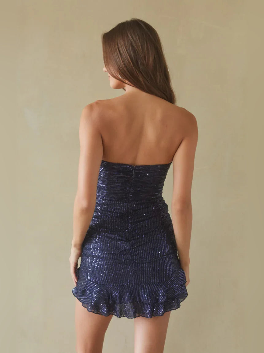 Back view of navy blue strapless sequin mini dress with ruched back and ruffled hem