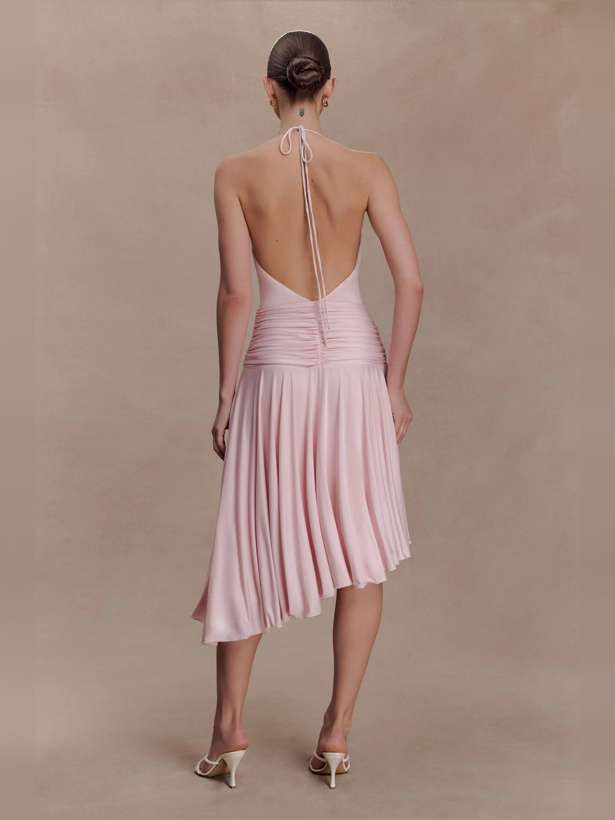 Pink halter midi dress with open back, tied waist, and pleated asymmetrical hem