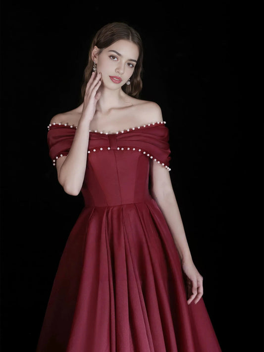 Burgundy off-shoulder corset dress with beaded trim at neckline and sleeve edges