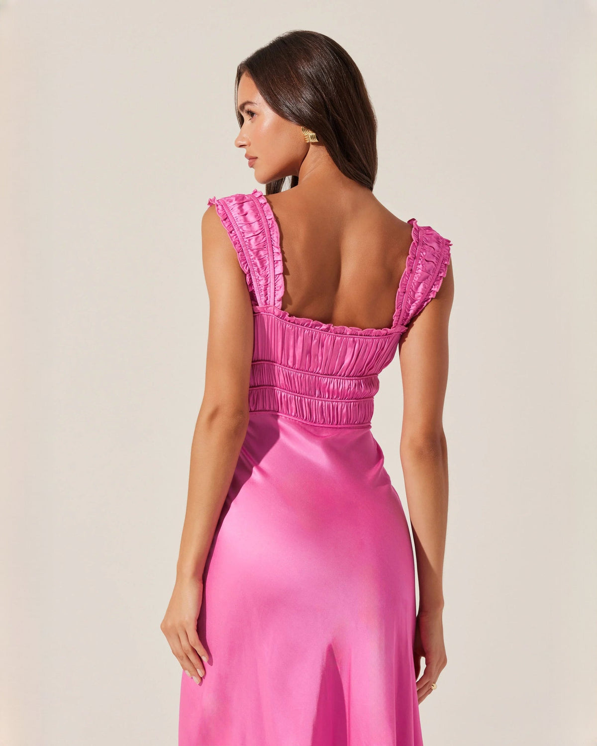 Pink satin backless-look midi dress with ruched back and ruffle-edge cap sleeves.