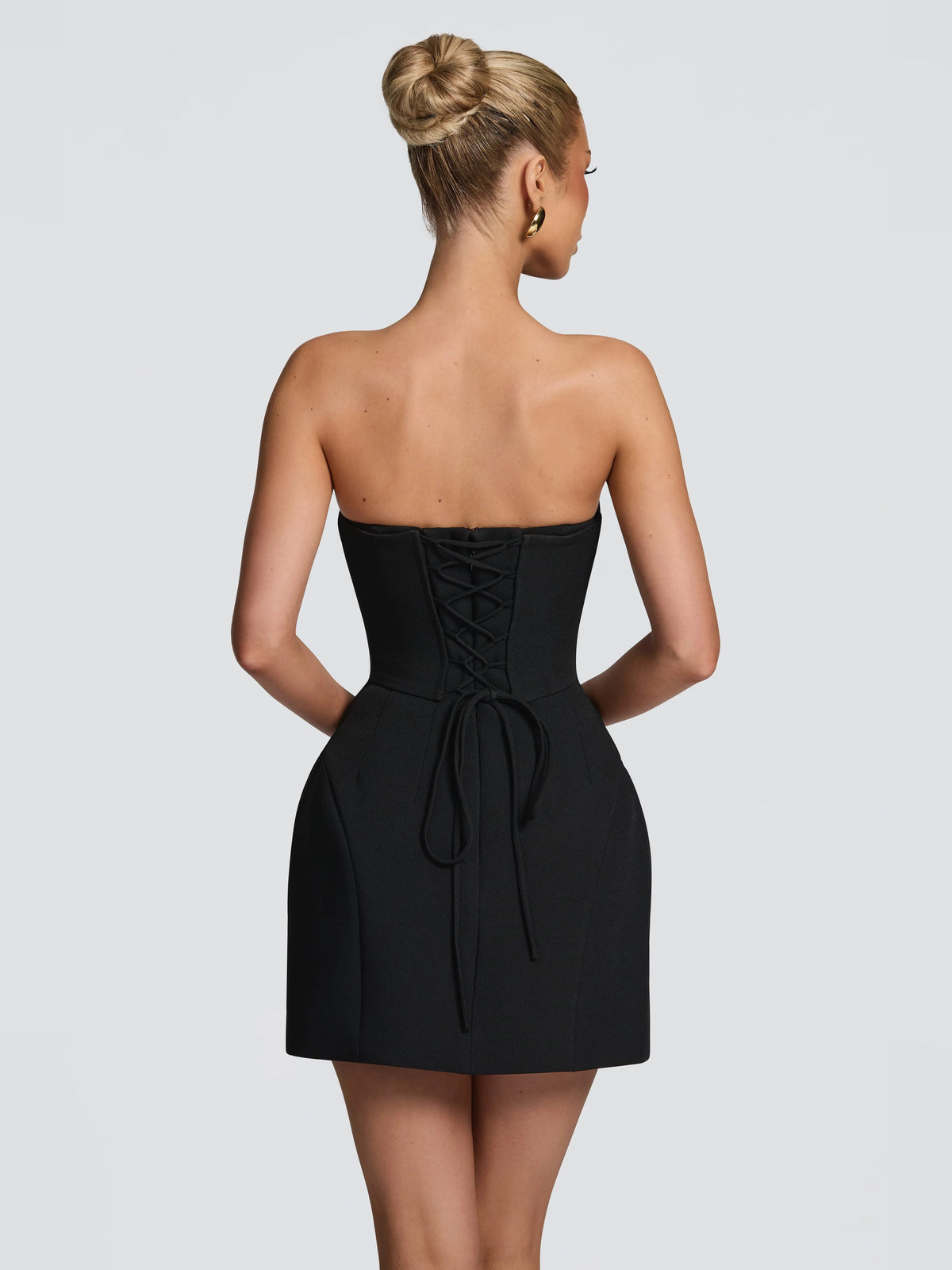 Black strapless mini dress shown from back with gathered bow-tie detail