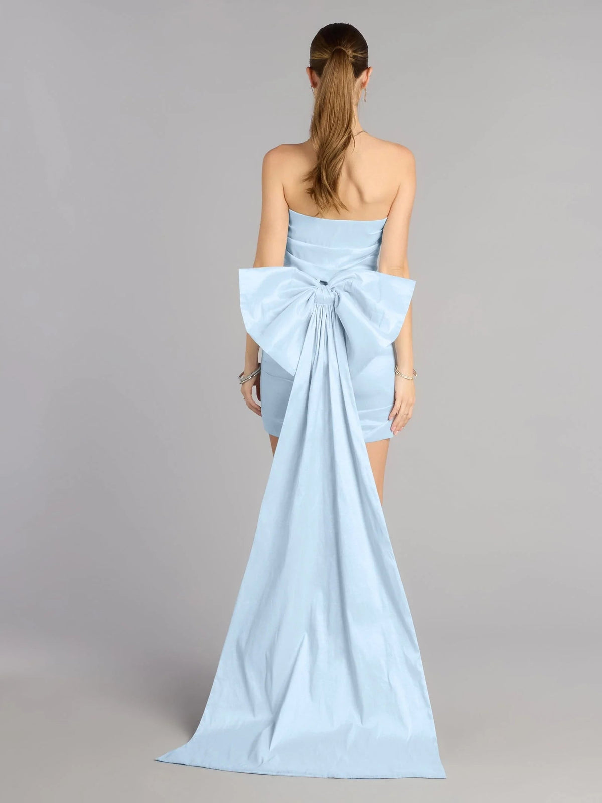 Sky-blue strapless satin mini dress, back view with large bow and long train