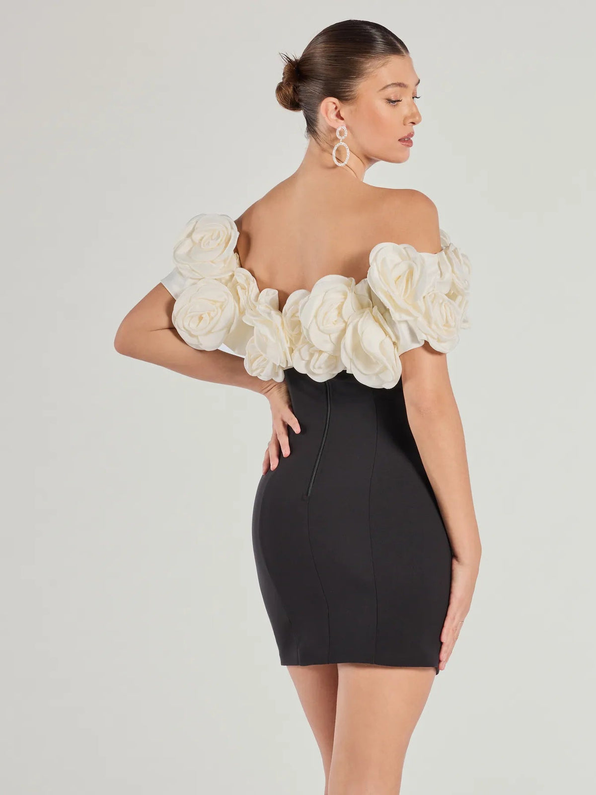 Black off-shoulder mini dress with cream rose rosette sleeve ruffles, side view
