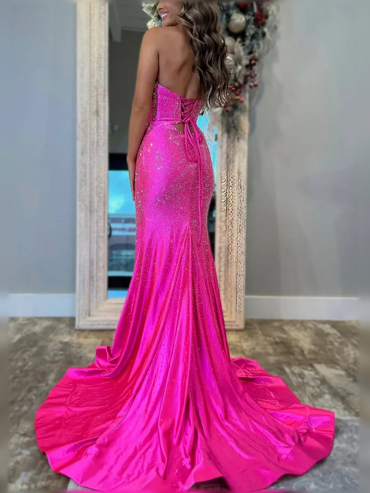 Hot pink sequin formal dress with open back, side slit, and flowing floor length hem