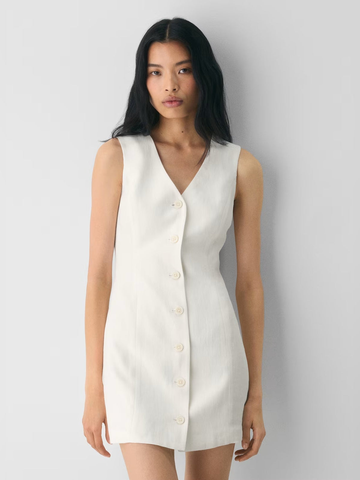 White V-neck sleeveless mini dress with visible front buttons