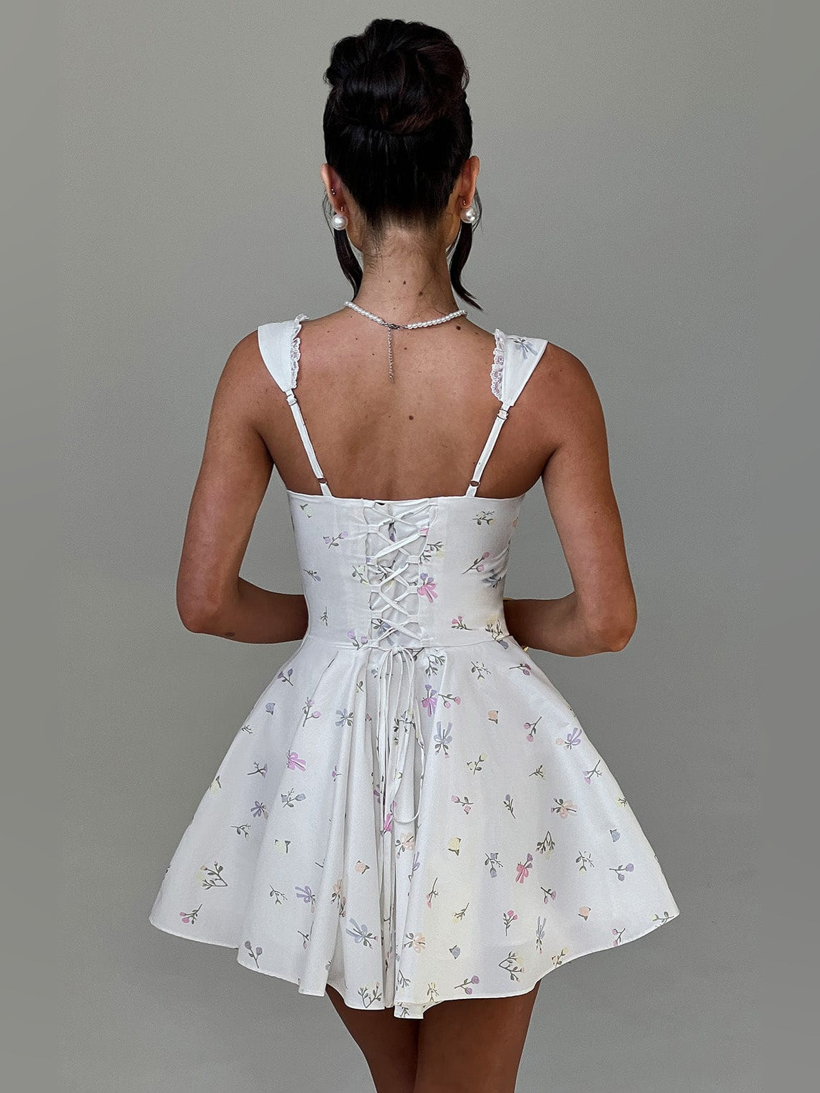White mini dress with floral print, lace straps, corset-style back and tied bow detail