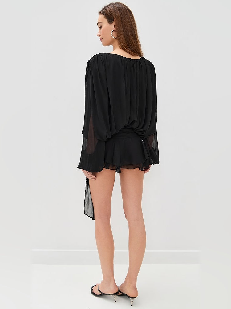 Black mini dress, back view, draped waist with flowing gathered skirt and sheer sleeves