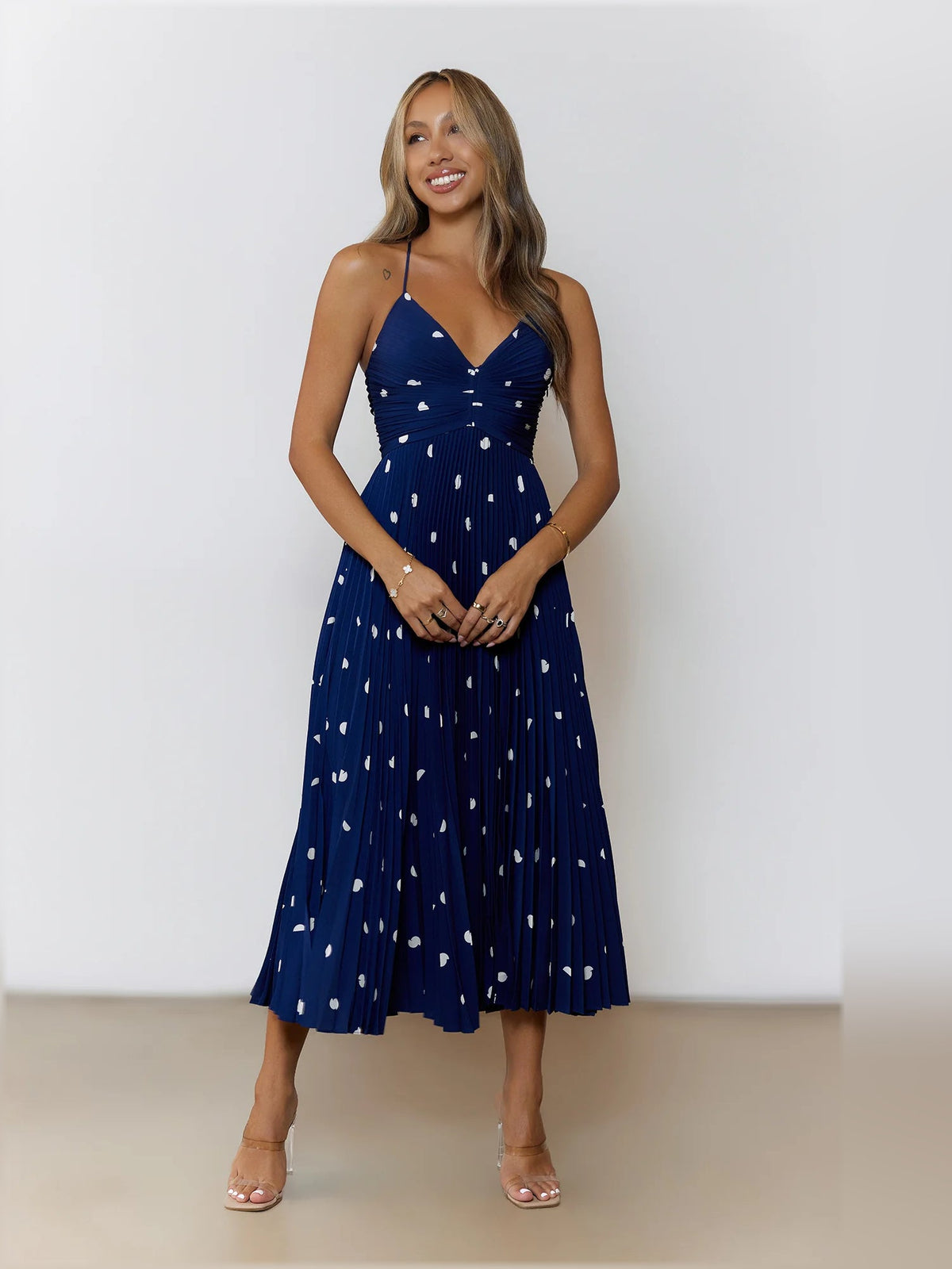Navy pleated midi dress with white dot print and thin spaghetti straps, full length