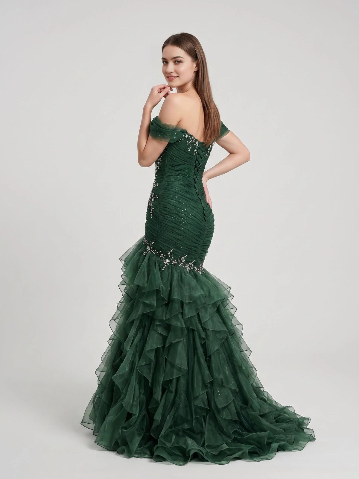Emerald green ruched off-shoulder corset gown with sparkling detail and layered ruffle skirt