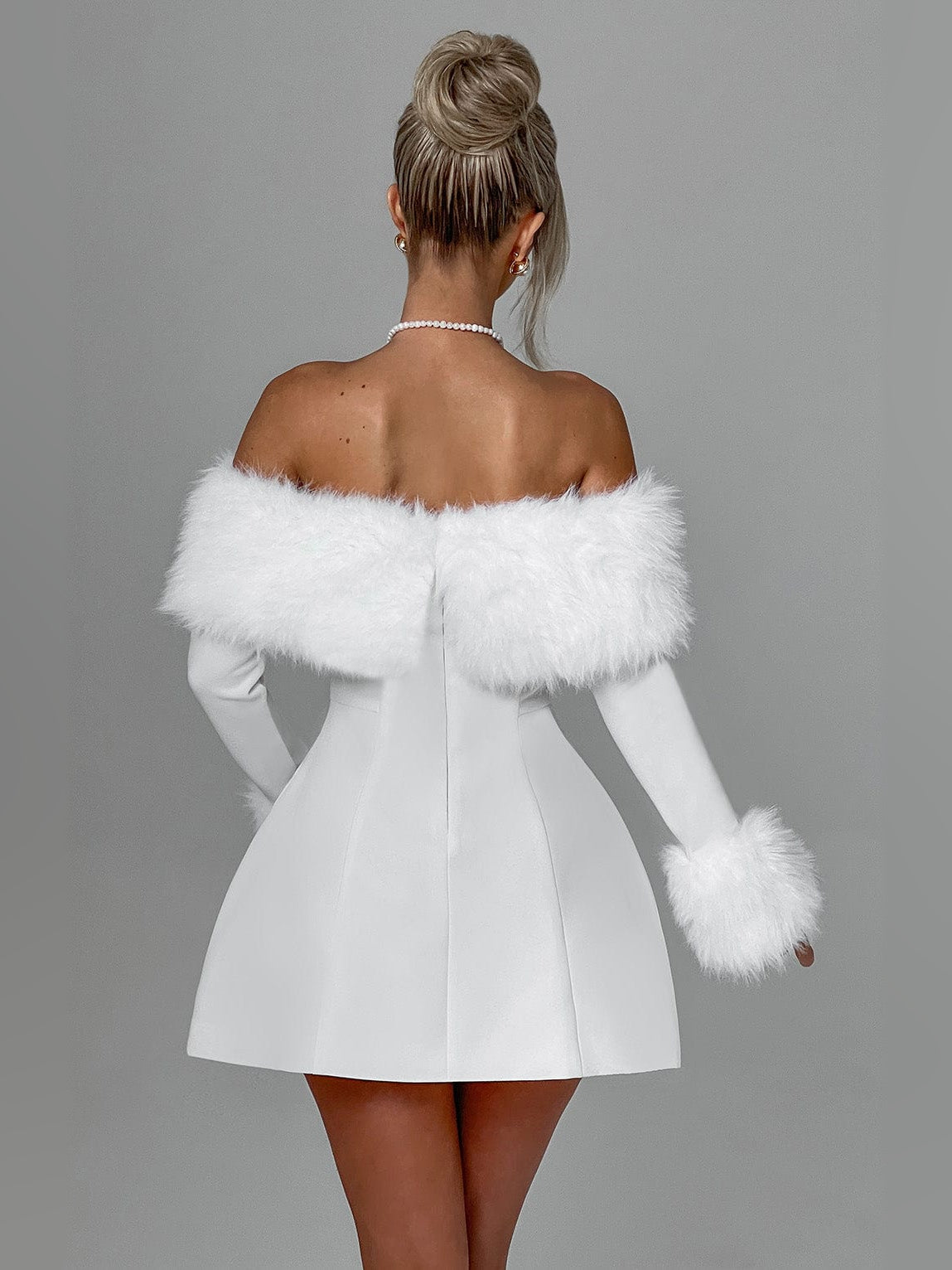 Back view of ivory mini dress with off-shoulder faux fur trim and flared skirt.