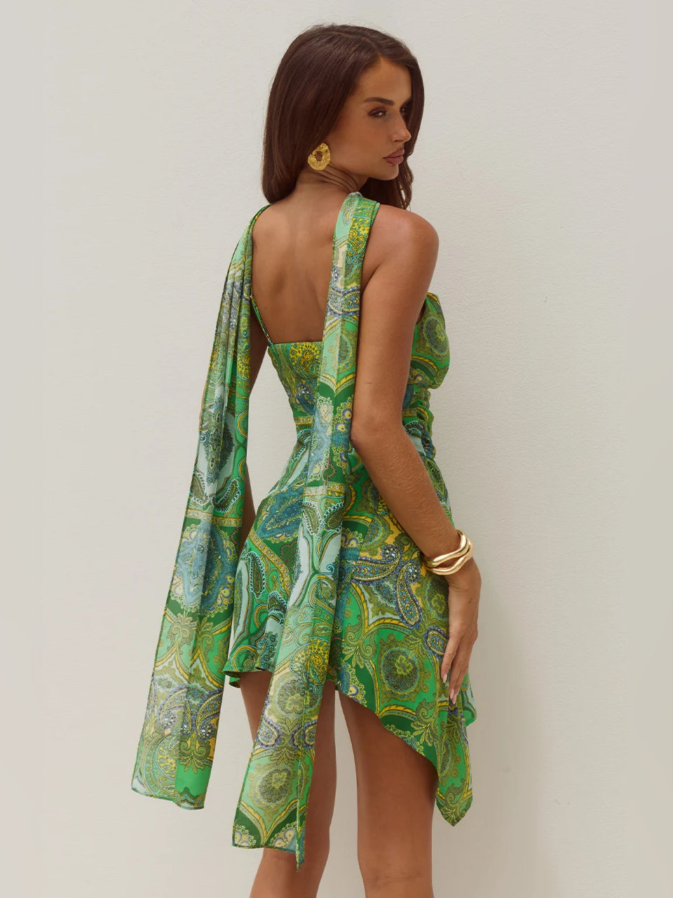 Back view of green paisley mini dress with scoop neckline, spaghetti straps, flowing drape