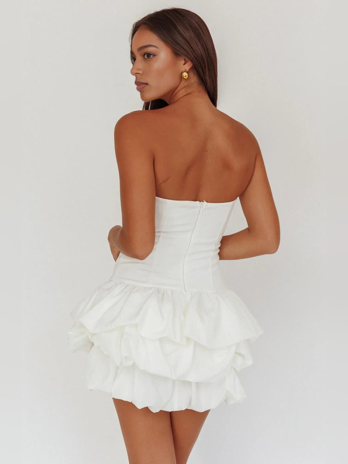 White strapless corset mini dress, tiered ruffle skirt; back view