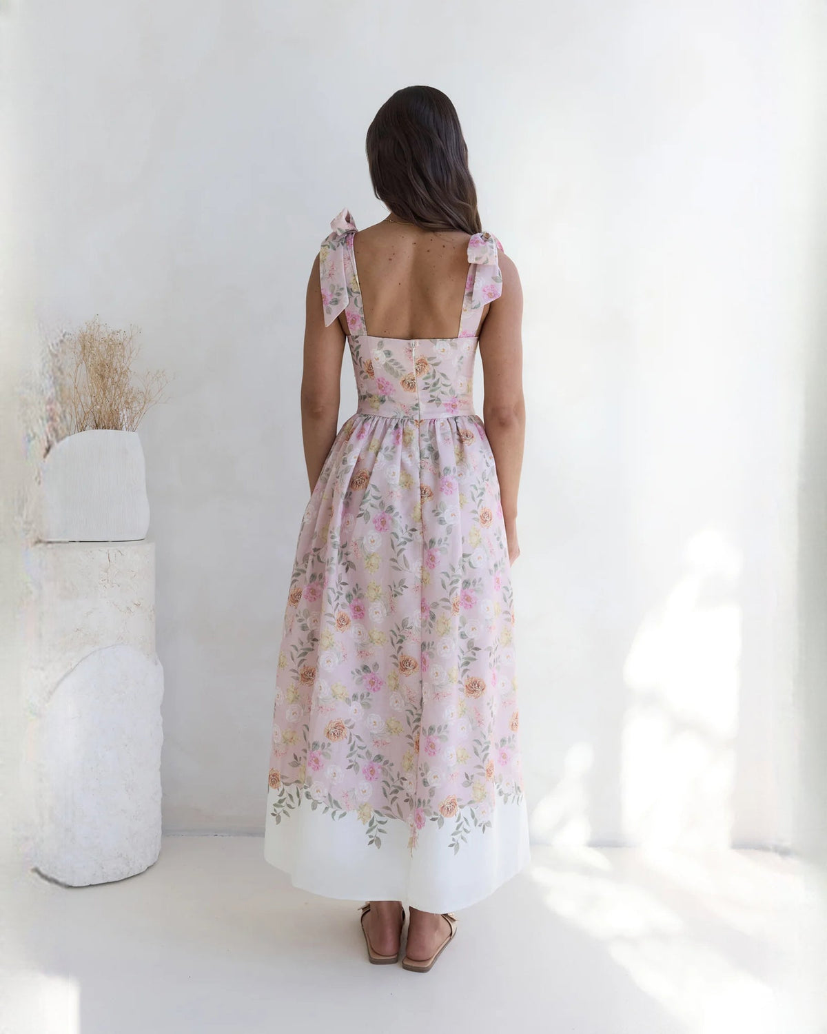 Back view of pink floral sleeveless satin A-line maxi dress with bow shoulder straps