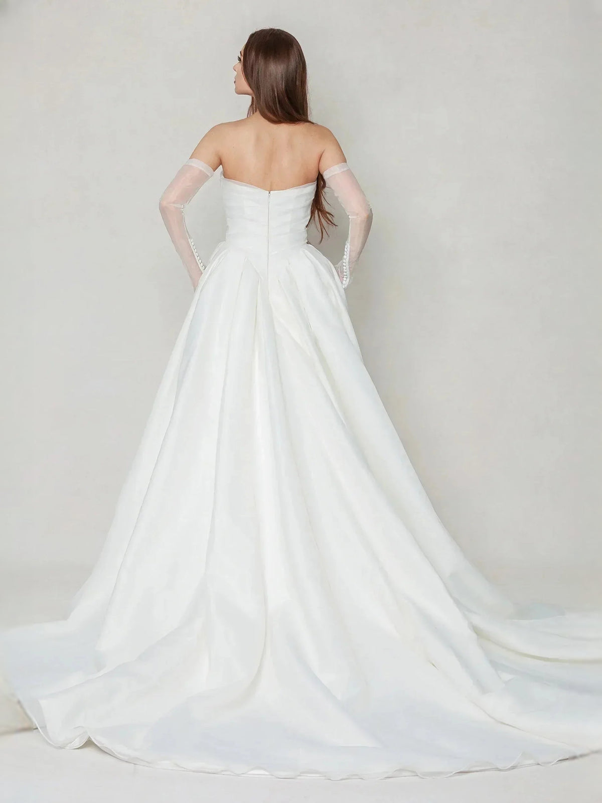 Ivory strapless wedding dress from back view with pleated full skirt and long train